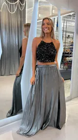 Pollera larga de satén plateado con acabado metalizado, corte evasé, cintura alta y tajo lateral profundo.