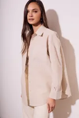 Camisa oversize color arena con rayas verticales marrones, de manga larga y cuello clásico.