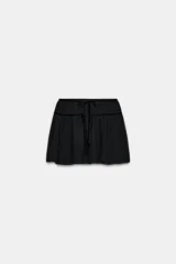 Falda mini de tiro medio confeccionada en georgette, con detalle de lazos de terciopelo a tono en la cintura. Presenta forro interior y cierre lateral con cremallera oculta.