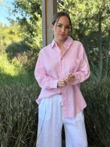 Camisa celeste a rayas verticales blancas, de corte holgado, manga larga y cuello camisero.