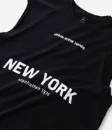 Musculosa masculina de corte boxy fit, confeccionada en algodón. Presenta cuello redondo, hombros ligeramente ampliados y acabado deshilachado en el ruedo. Cuenta con estampa frontal con la frase 'Urban Scene Trends' y el texto 'New York Manhattan 1974' en el centro.