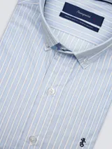Camisa de hombre clásica de manga larga, confeccionada en 100% algodón, con diseño de rayas verticales en tonos azul, celeste y blanco, cuello abotonado y bordado sutil en el pecho.