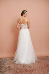 Vestido largo blanco de alta costura, con corset estructurado de tirantes finos con apliques florales y falda amplia de tul con brillo.