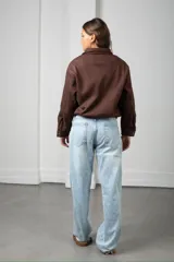 Campera corta de gamuza color marrón, con cierre frontal, cuello camisero y bolsillos frontales con solapa.