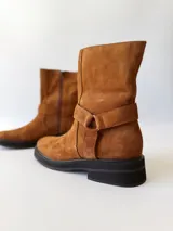 Bota corta de cuero color camel, con correa decorativa alrededor del tobillo y suela de goma negra.