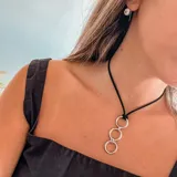 Collar con cordón negro y tres aros plateados.