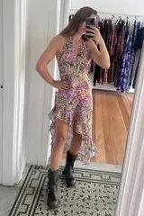 Vestido midi con diseño asimétrico, escote halter con tiras ajustables y espalda descubierta. Presenta un estampado floral multicolor y falda con volados en el ruedo.