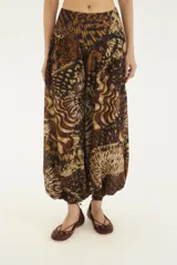 Pantalón babucha de tiro alto con silueta amplia, puños ajustados en los tobillos y estampado de inspiración tropical en tonos marrones y negros.
