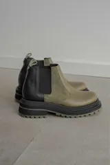 Botas tipo Chelsea con diseño bicolor en tonos negro y verde oliva. Presentan paneles laterales elásticos, suela track robusta y tirador trasero.