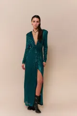 Vestido largo de lentejuelas color verde esmeralda, con escote en V profundo, mangas largas y tajo lateral en la falda. Presenta un diseño cruzado con fruncido en la cintura.