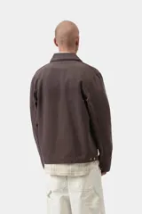 Chaqueta Detroit de Carhartt WIP color marrón, de corte recto con cierre frontal de cremallera, cuello clásico de pana y bolsillos laterales. Cuenta con un bolsillo con cierre en el pecho decorado con la etiqueta del logo de la marca.