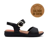 Sandalia de cuero color negro con suela marrón, tira ancha sobre los dedos y tira al tobillo con hebilla dorada.