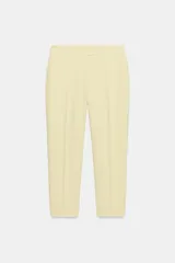 Pantalón de tiro alto color amarillo pastel, de corte recto y largo tobillero, con bolsillos delanteros y pliegues marcados.