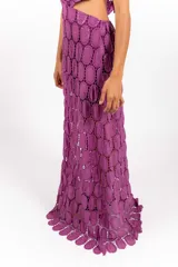 Vestido largo de encaje con patrón circular, color lila, de corte halter con tiras cruzadas al cuello y aberturas laterales en la cintura.