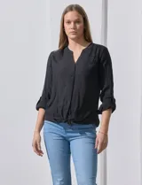 Blusa blanca de gasa marca Zac & Rachel, con cuello a la base, escote en V, abertura central con botones, bolsillo aplicado en el pecho y mangas largas regulables con presilla y botón. Tiene terminación opcional de nudo en el ruedo.