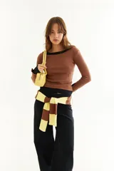 Top de manga larga con diseño de doble capa superpuesta, combinando una capa superior negra y una inferior marrón. Presenta cuello redondo, ajuste al cuerpo y detalle de bordado BG en la parte inferior.