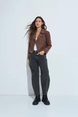 Campera estilo biker de símil gamuza color marrón, con cierre frontal y detalles de tachas metálicas en solapas, mangas y ruedo.