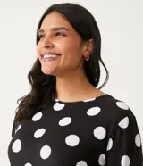 Pijama de dos piezas con estampado de lunares blancos sobre fondo negro. Incluye una blusa de manga larga con cuello redondo y un pantalón largo con cintura elástica y cordón ajustable.