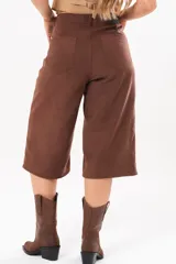 Bermuda de silueta amplia y tiro medio, color marrón chocolate, con bolsillos delanteros y traseros, cierre frontal con cremallera y botón.