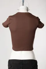 Baby tee de calce al cuerpo y manga corta, con cuello redondo y diseño con tachas frontales.