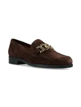 Mocasín de gamuza color marrón oscuro, con detalle de herraje metálico dorado en el empeine y suela plana de goma negra.