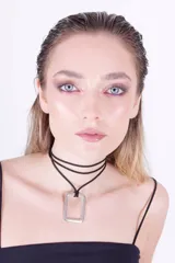 Gargantilla de cuero negro con dije rectangular plateado.