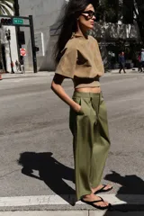Pantalón de tiro alto con corte recto, bolsillos delanteros y detalle de pinzas con botones en la cintura. Cuenta con cierre frontal de cremallera y gancho metálico.