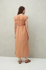 Vestido largo color salmón con estampado abstracto, escote con lazo y mangas cortas. Diseño fluido con frunces en el pecho.