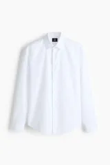 Camisa blanca de manga larga con cuello inglés y corte slim fit. Cuenta con cierre frontal de botones y bajo redondeado.