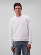 Buzo de Calvin Klein color blanco, confeccionado en algodón regenerado, con cuello redondo, puños y dobladillo de punto canalé y un mini monograma en parche en el pecho.