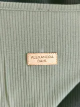 Vestido largo de morley fino, con corte asimétrico en bloques de color verde, negro y blanco, de mangas largas y calce amplio.