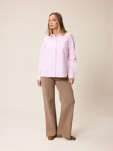 Pantalón jean de tiro alto y corte recto, color marrón chocolate, con aberturas laterales en el ruedo.