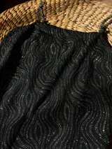 Vestido negro con estampado de ondas plateadas y tirantes de cadena metálica.