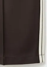 Pantalón deportivo negro con líneas blancas laterales, tiro alto y diseño recto.