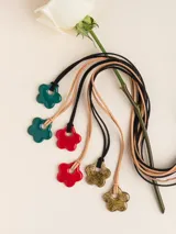 Collar de tiento de cuero con dije de porcelana en forma de flor esmaltada en rojo.