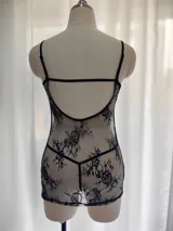 Babydoll de encaje negro semitransparente con diseño floral, tirantes finos regulables, escote con costura de realce y espalda descubierta. Incluye una tanga a juego.