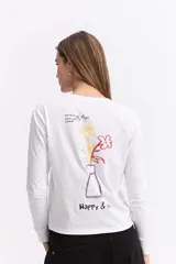 Remera de manga larga color blanco con estampa artística en la espalda que representa un florero con flores de colores y texto.