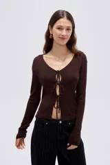 Top de manga larga en tejido de punto con lurex, color negro, de corte ajustado al cuerpo, con escote en V pronunciado y cierre delantero mediante finos lazos para anudar.
