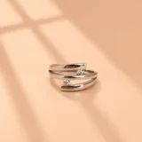 Anillo de plata 925 con diseño abierto de bandas cruzadas, decorado con dos piedras de circonia cúbica en los extremos.