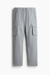 Pantalón cargo de nylon color gris, con cintura elástica con cordón ajustable, bolsillos laterales con cierre y bolsillos en las piernas con solapa.