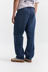 Jean de corte baggy con tiro medio, diseño amplio y holgado en piernas y cadera, con pasacintos y cierre frontal.