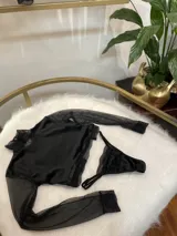 Conjunto de lencería compuesto por un top de cuello alto con mangas largas de microtul y detalles de encaje, y una tanga regulable de terciopelo y encaje.