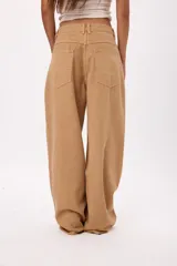 Jean de corte wide leg en color beige, con cintura de tiro medio y diseño de cinco bolsillos.