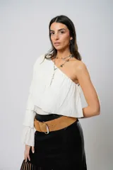 Blusa blanca con un hombro descubierto, manga larga con volados y textura arrugada.