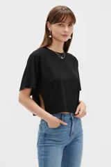 Remera negra de algodón, con cuello redondo, mangas cortas amplias y aberturas laterales en el torso.