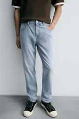 Pantalón de jean corte slim fit, color gris con efecto lavado. Presenta diseño de cinco bolsillos, cierre frontal con cremallera y botón, y tejido elástico.