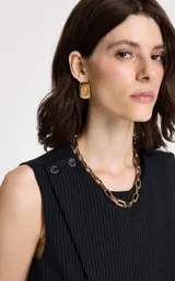 Chaleco sastrero de corte entallado con diseño de raya diplomática vertical. Presenta cuello redondo, sisas sin mangas, detalle cruzado asimétrico en el frente, botones decorativos en el hombro izquierdo y cinturón de tela a juego con hebilla metálica.