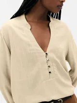 Blusa color marrón claro, con cuello mao y escote en V, manga 7/8 con puños elásticos y cierre frontal parcial con botones.