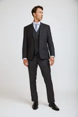 Traje de tres piezas compuesto por saco, chaleco y pantalón de corte sastre. El conjunto presenta un diseño en color gris oscuro con un sutil patrón de cuadros gales, ideal para eventos formales.