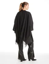 Ruana de tejido soft color negro, con detalles de brillos y tachas en los bordes frontales. Presenta una caída fluida y terminación con flecos.